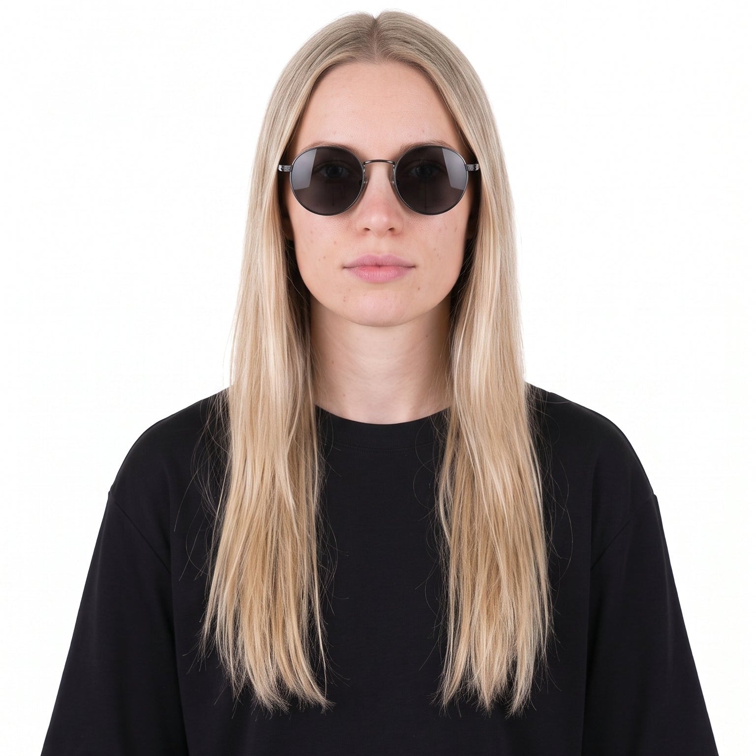 A woman with long blonde hair wearing a plain black short-sleeve t-shirt and round black sunglasses, standing against a solid white background.